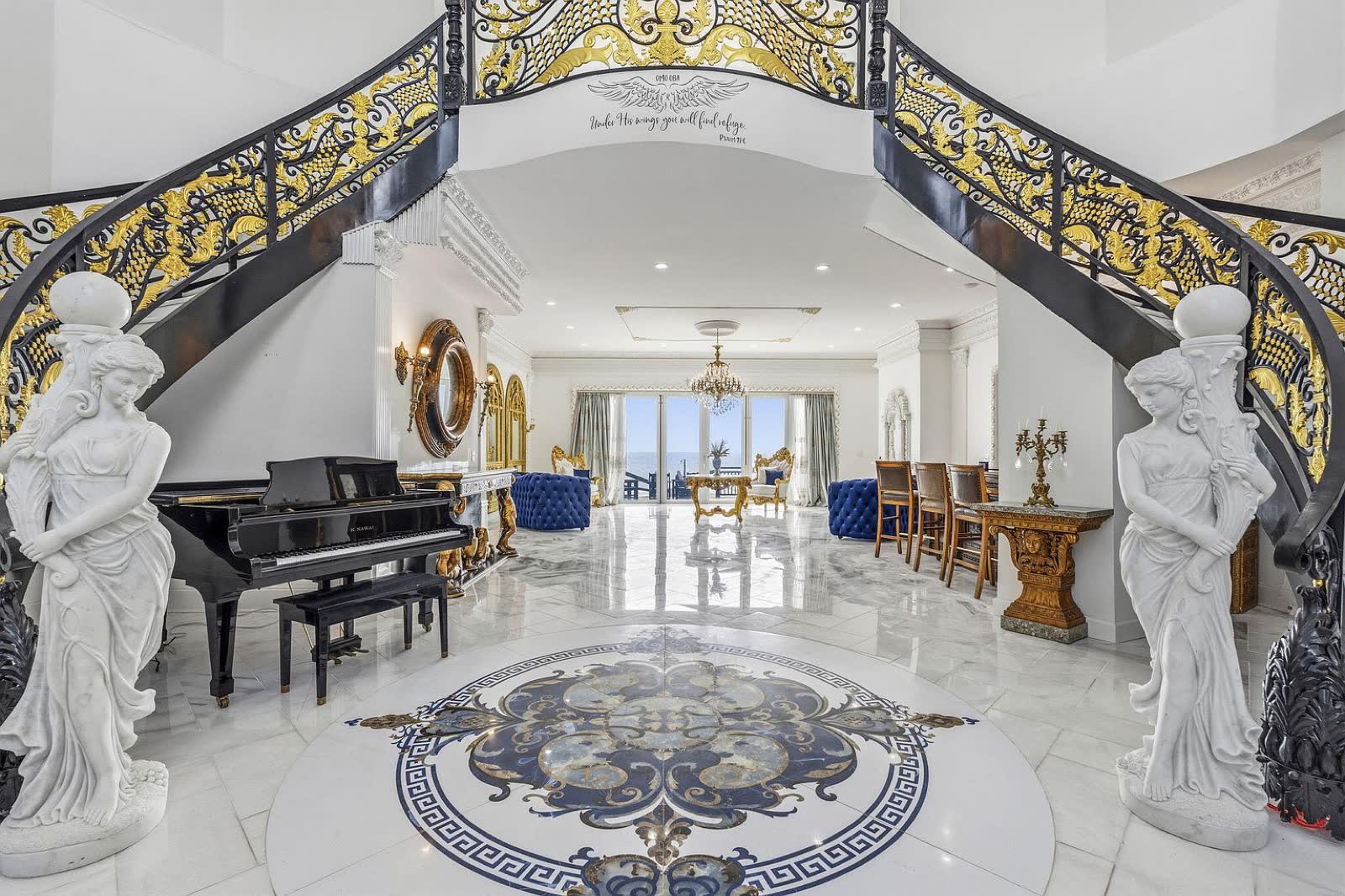 Grand foyer with twin wrought-iron staircases and a grand piano